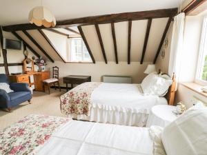 a bedroom with two beds and a blue chair at White Cottage in Hopton Wafers