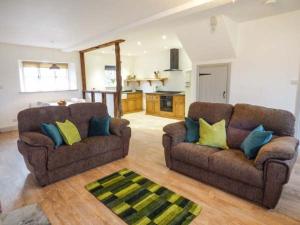 a living room with two couches and a kitchen at The Hayloft in Kendal