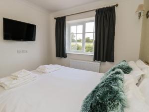 a bedroom with a white bed with a blanket on it at Swan Cottage in Fearby