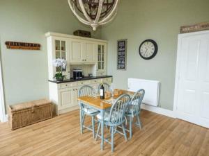 a kitchen with a table and chairs and a clock on the wall at The School House in Cockermouth