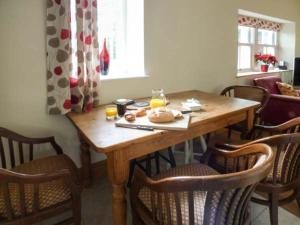 a wooden table with some food and orange juice on it at Old Hall Cottage in Settle