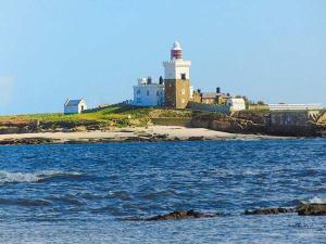 a lighthouse on the shore of a body of water at Corner Cottage in Amble