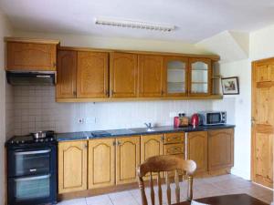 uma cozinha com armários de madeira, um fogão e uma cadeira em High Tide em Belmullet