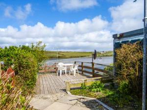 um pátio com uma mesa e cadeiras ao lado de um corpo de água em High Tide em Belmullet