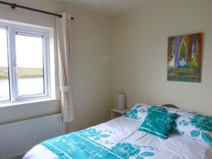 um quarto com uma cama, uma janela e uma colcha. em High Tide em Belmullet