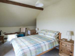 a bedroom with a bed and a table with a lamp at Y Stabal in Chwilog
