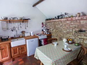 cocina con mesa y pared de piedra en The Smithy, en Leominster