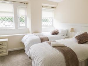 two beds in a room with two windows at Wesley Cottage in Keighley