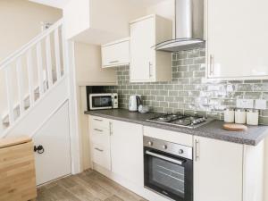 a kitchen with white cabinets and a stove top oven at Wesley Cottage in Keighley