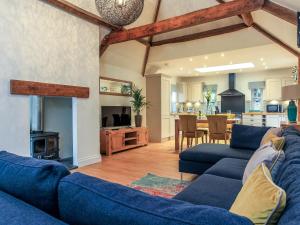 a living room with two blue couches and a kitchen at Woodmans Cottage Nables Farm in Chippenham