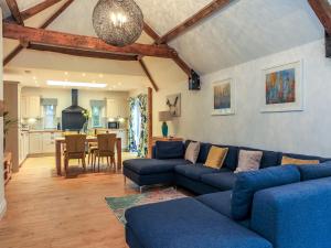 a living room with blue couches and a kitchen at Woodmans Cottage Nables Farm in Chippenham