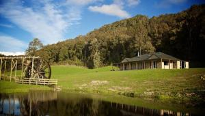 a house on a hill next to a body of water at Ahaura Lodge & Waterwheel Farm Stay in Totara Flat