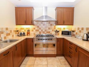 uma cozinha com armários de madeira e um forno com placa de fogão em The Annexe em Beeston