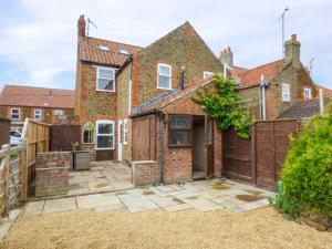 a brick house with a fence and a yard at Fern Cottage in Heacham