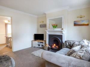 a living room with a couch and a fireplace at Fern Cottage in Heacham