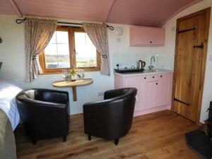 a bedroom with two black chairs and a kitchen at Llety'r Bugail in Holyhead