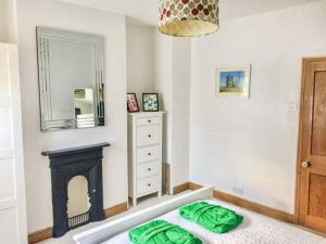 a bedroom with a fireplace and a bed with green sheets at Croft Cottage in Pateley Bridge