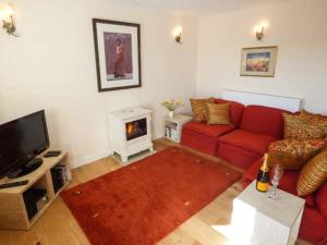 a living room with a red couch and a fireplace at Kestrel Cottage in Grange Over Sands
