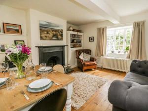 a living room with a table and a fireplace at Rose Cottage in Bakewell