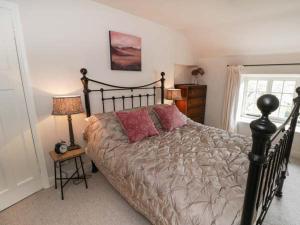 a bedroom with a bed with two red pillows on it at Rose Cottage in Bakewell