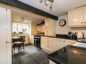 a kitchen with white cabinets and a clock on the wall at Rose Cottage in Bakewell