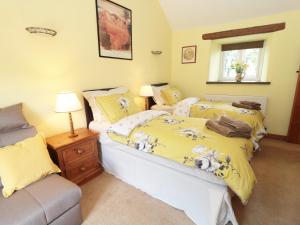 キャッスルトンにあるButtercup Cottageのベッドルーム1室(ベッド2台、窓、ソファ付)