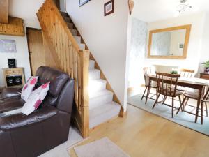 a living room with a staircase and a leather chair at 60 Hyfrydle Road in Caernarfon