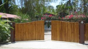 a wooden gate in front of a yard with flowers at Coloso del Mar in Zancudo
