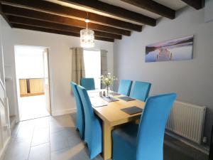 a dining room with a wooden table and blue chairs at Minffordd in Bala