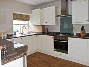 a kitchen with white cabinets and a stove top oven at Rose Cottage in Grassington