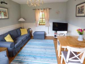 a living room with a blue couch and a table at Stable Cottage in Withernwick