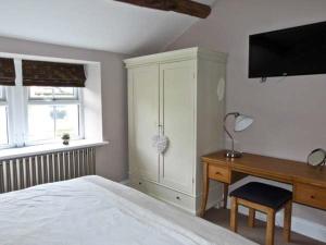 a bedroom with a bed and a desk and a tv at Rose Cottage in Grassington