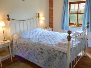 a bedroom with a white bed with blue curtains at Stable Cottage in Withernwick