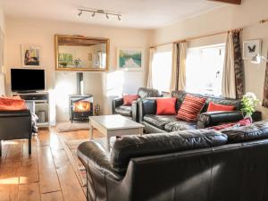 a living room with leather couches and a fireplace at Beulah Cottage in Cinderford