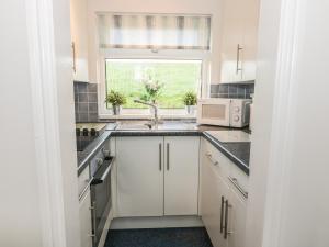 een keuken met witte kasten, een wastafel en een raam bij Hideaway in Haverfordwest
