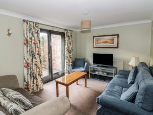 a living room with a blue couch and a tv at The Lodge off High Street in Hadleigh