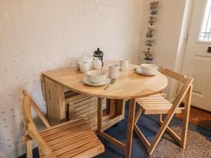 una mesa de madera con 2 sillas y un set de té. en Quarterdeck en Scarborough