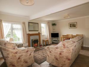 a living room with two couches and a fireplace at Polurrian in Helston