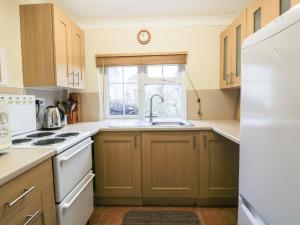 a kitchen with wooden cabinets and a sink and a window at Polurrian in Helston