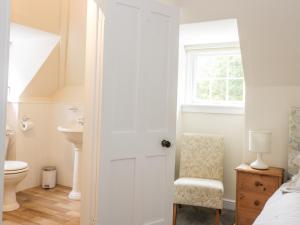 a white bathroom with a toilet and a chair at East Lodge in Walkerburn