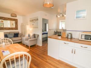a kitchen and living room with a couch and a table at Wren Cottage in Ilfracombe +7 photos