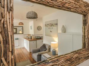 a living room with a chair and a kitchen at Wren Cottage in Ilfracombe