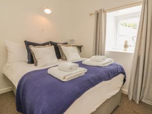 a bedroom with a bed with towels on it at Wren Cottage in Ilfracombe