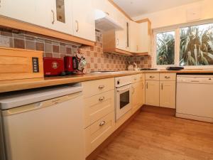 a kitchen with white cabinets and a window at Bryn Lleuddad in Llangwnadl