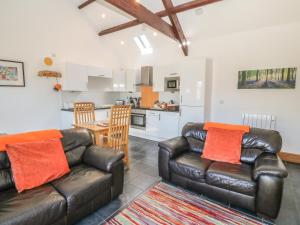 a living room with two leather couches and a kitchen at Bwthyn Bach in Llanddwywe