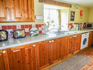 una cocina con armarios de madera y fregadero en Mary's Cottage, en Kentisbury