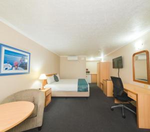 ein Hotelzimmer mit einem Bett und einem Schreibtisch in der Unterkunft Harbour Sails Motor Inn in Gladstone