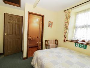 a bedroom with a bed and a bathroom at Gardeners Cottage in Hesket Newmarket