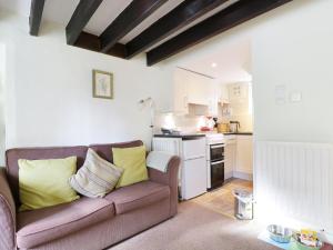 ein Wohnzimmer mit einem Sofa und einer Küche in der Unterkunft Nightingale Cottage in Threlkeld