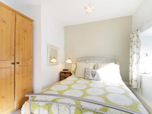a bedroom with a bed with a green and white bedspread at Nightingale Cottage in Threlkeld